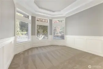 The dining room features a built-in buffet with two display shelves, gorgeous chandelier and accent lights, bay window, wainscoting, coved ceiling and easy access to both the kitchen and formal living room.