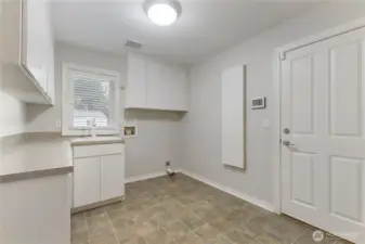 The large utility room features lots of cabinet and counter space, built-in iron board, utility sink and easy access to the garage.