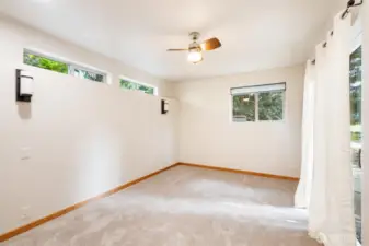 The bedroom in the ADU has lots of windows and a sliding door onto a private patio.