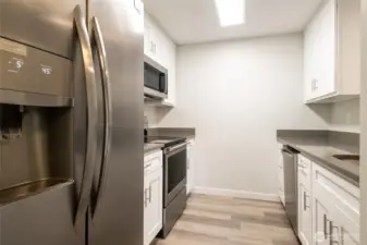 Kitchen features brand new cabinetry + stainless steel appliance suite (fridge, range, dishwasher and microwave). New quartz countertops.