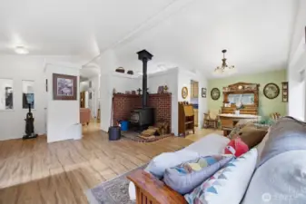 Another view of the living room with the wood burning freestanding wood stove and the dining room to the right.