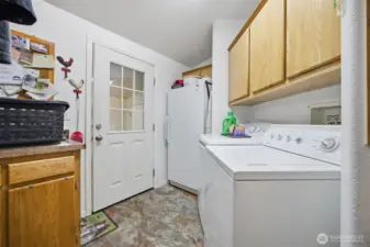 The laundry room is spacious and has a lot of cabinets and some additional counter space. This is the back door and there is a storage room addition.