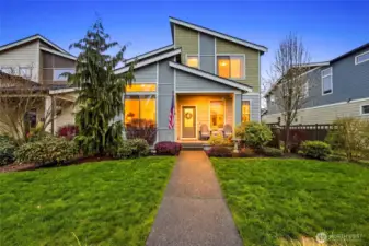 Inviting front elevation at dusk showcasing warm lighting, manicured lawn, and strong curb appeal in this Black Diamond WA home near parks, trails, and future amenities.