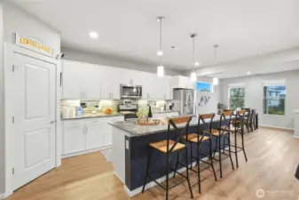 Large modern kitchen featuring granite countertops, oversized island seating, stainless appliances, and ample cabinet storage designed for entertaining.