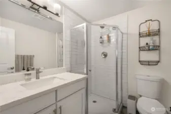 Newer vanity, quartz counter, tiled shower, new toilet and ceramic tiled flooring with updated light fixture in this updated bathroom