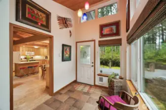 Vaulted foyer with wood ceiling, pendant lights, ceramic tile floor & wall of windows!