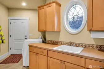 Large main floor laundry room with cabenters, utility sink and tons of storage.  Washer and Dryer (gas) stay.