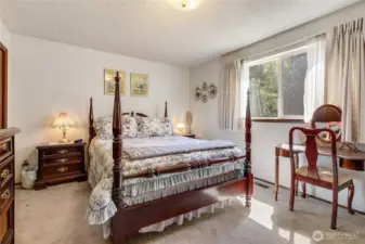 A primary bedroom with a sunny window- a nice way to wake up in the morning