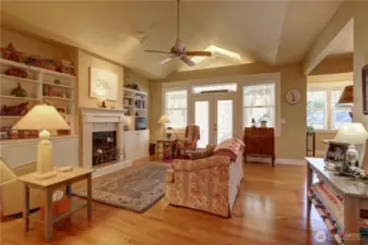 Vaulted Great Room features Built-ins, Hardwood Flooring, Ceiling Fan, Gas Fireplace and Opens to the Sun Room. Breakfast Nook and Kitchen to the Right.