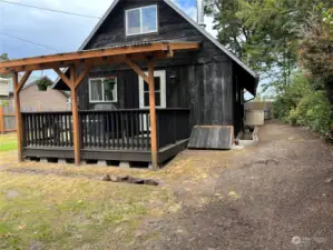 East side of house with wood storage convenient to the house entrance, hose storage on side and generator box in background. Wiring is provided to the inside of house.