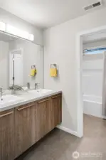 A full bath is centrally located between the bedrooms and is divided into two sections for the ease of multiple users.  There is a long vanity counter with two raised square sinks. Section two is where the bathtub/shower and toilet are located.      A walk-in linen closet in the main hallway provides additional storage.