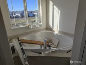 Large soaking tub in one of the primary bathrooms. Has water damage over window.