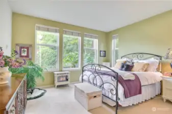 Primary bedroom has large windows, beautiful views of nature, and lots of wall space.
