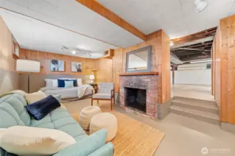 Full of charm, this basement living area features warm wood paneling, a classic wood-burning fireplace, and space to relax, host guests, or unwind by the fire.
