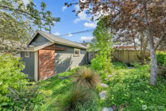 Tucked away in a quiet corner of the yard, this one-car detached garage is surrounded by lush greenery and offers both extra storage and a serene space to garden, tinker, or simply unwind.