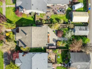 Aerial view captures the full layout of the home and backyard oasis—showcasing the lush landscaping, stone paths, and generous patio space.