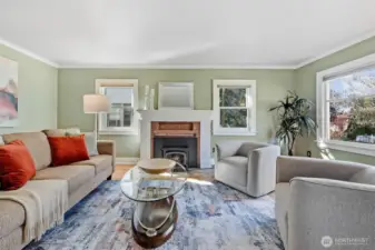 This charming living space features a classic wood-burning fireplace and period-matching Marvin double-pane windows. Abundant natural light pours in through multiple windows, creating a warm, inviting atmosphere.