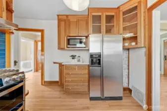Generous storage in this charming kitchen, complete with stainless steel fridge, built-in microwave, and elegant glass-front cabinets for displaying your favorite pieces.