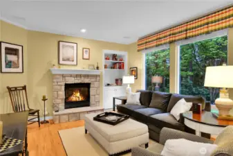 Family room. 9-foot ceiling with crown moulding, built-in speakers. Oversized windows look out to private yard, forested park behind. English Castle Stone gas-log fireplace with raised hearth, built-in bookcase with paneled cabinet. Oak-hardwood floor.