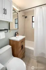 Updated full bathroom with ceramic tile floor and tub surround, new vanity, mirror and hardware.