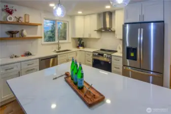 Stunning fully remodeled kitchen with quartz countertops, stainless appliances, open shelving, and a generous island perfect for prep and gathering.