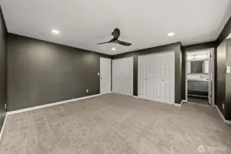 This view of the primary suite highlights its open layout and convenient access to the beautifully updated main bathroom. And a sleek ceiling fan enhance both comfort and functionality.