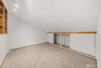 This versatile loft area offers built-in shelving and extra storage behind sliding doors, making it perfect for organization or creative use. Soft carpeting and recessed lighting enhance the comfort and functionality of this unique space.