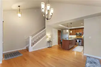 Alternate view of the flexible front living space with oak hardwood floors recently cleaned and buffed, showing access to the upper level where additional bedrooms and bath are located. Photo depicts the room without furniture; seller furnishings are currently in the home.