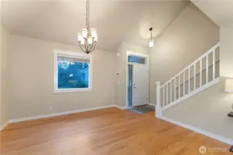 South-facing front living space with oak hardwood floors recently cleaned and buffed, suitable for a sitting room or dining area and located near the front entry. Photo depicts the room without furniture; seller furnishings remain in the home.