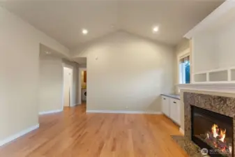 Alternate view of the living room showing the hallway that leads to the main-floor powder bath and primary bedroom, highlighting the convenient main-level living layout. Photo depicts the room without furniture; seller furnishings are currently in the home.