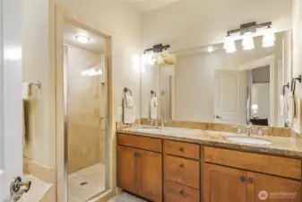 Spacious five-piece primary bathroom with walk-in travertine tile shower, and dual sink vanity.
