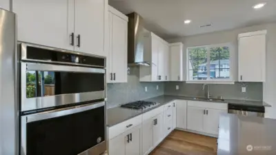This kitchen is complete with stainless appliances including a five burner gas cooktop and sleek hood.