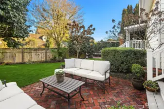 Fenced backyard English Garden with lush level grassy yard, mature plantings and French-style raised planters for organic edible gardening.