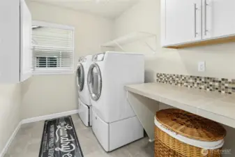Upper level laundry room with folding counter and cabinets.