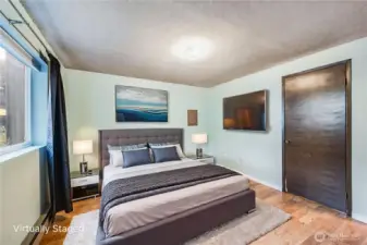 The bedroom is a spacious room with wood laminate flooring.