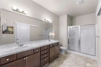 Large primary bathroom with enclosed standing shower, dual vanity and full length mirros, plenty of storage and large walk in closet