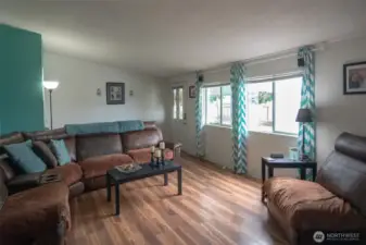 Enter to cheerful living room with laminate flooring and vaulted ceilings.