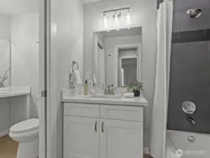 A pocket door divides the bathroom for additional privacy. Each side has its own vanity. The newly tiled shower creates a zen feeling.