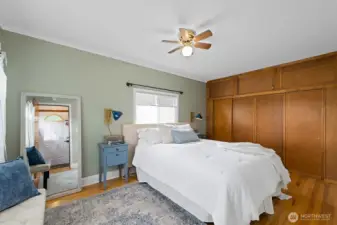 Largest bedroom with wall to wall closets, filled with natural light, featuring hardwood floors, calming green tones and a cozy atmosphere for restful nights
