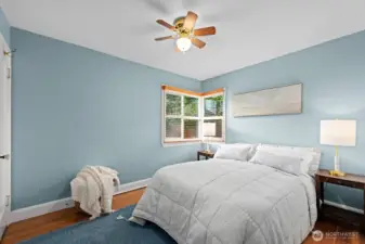 Secondary bedroom with hardwood floors, calming blue walls, and corner windows that bring in abundant natural light