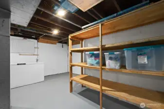 Clean, freshly painted basement with sturdy built-in shelving and laundry hookups—perfect for storage, hobbies, or future expansion