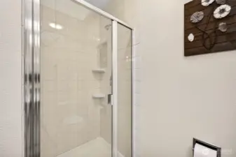 The primary 3/4 bath features a glass enclosed shower with clean tile surround and practical built in shelving for daily essentials. Simple, durable finishes make this a low maintenance space that holds up well over time.