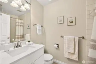 The full hall bath is bright and clean, featuring a wide vanity with generous counter space, modern lighting, and crisp fixtures. A tub and shower combo with tile surround makes this bathroom practical for everyday use, guests, and weekend routines.