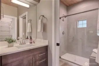 Primary bath with tiled shower and seating bench.