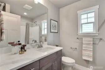 Full guest bathroom with quartz countertops.