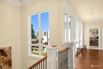 An elegant staircase and large windows greet you at the top of the stairs.