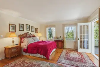 Main Level Primary bedroom with French doors opening to a covered sitting area