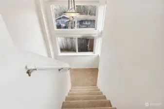 Let the chandelier set the tone as you climb the carpeted stairs, leading you to this charming landing nook. Four windows bring the outside in, and the soft white walls and carpeted floors make this space feel as quiet and inviting as it looks.