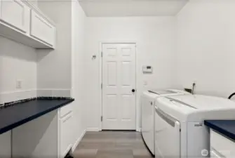 Clean and functional laundry room comes with loads of storage and convenient folding counter.