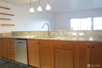 VIEW OF THE OTHER SIDE OF THE KITCHEN WITH SS DISH WASHER, ADDITIONAL CABINETRY AND DRAWERS AND GRANITE COUNTER TOPS.